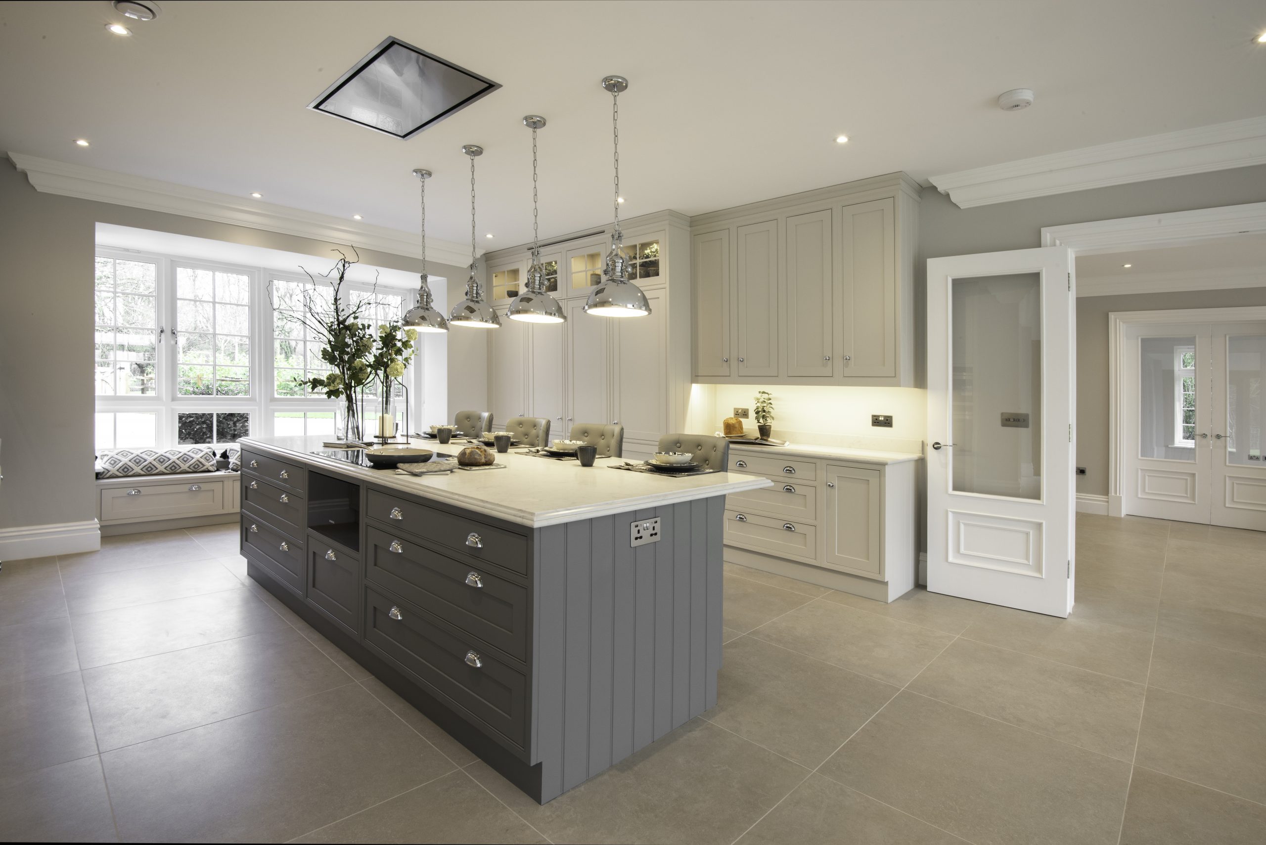 Soft grey kitchen with large island for seating, storage and housing appliances. 