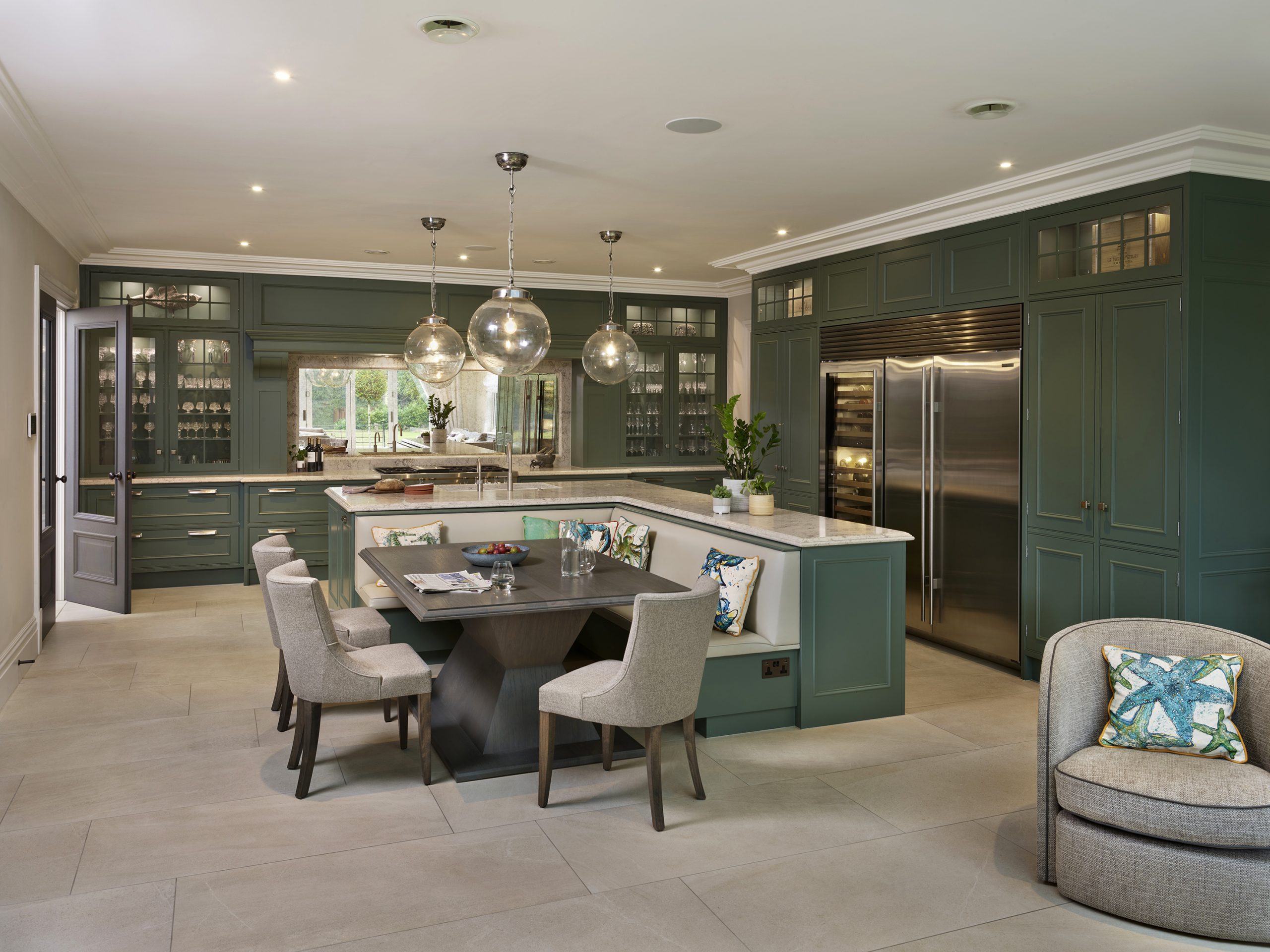 Classic englemere kitchen in deep green with banquette seating integrated into the island. Sub zero and wolf appliances in this kitchen add to the luxury aesthetic.  