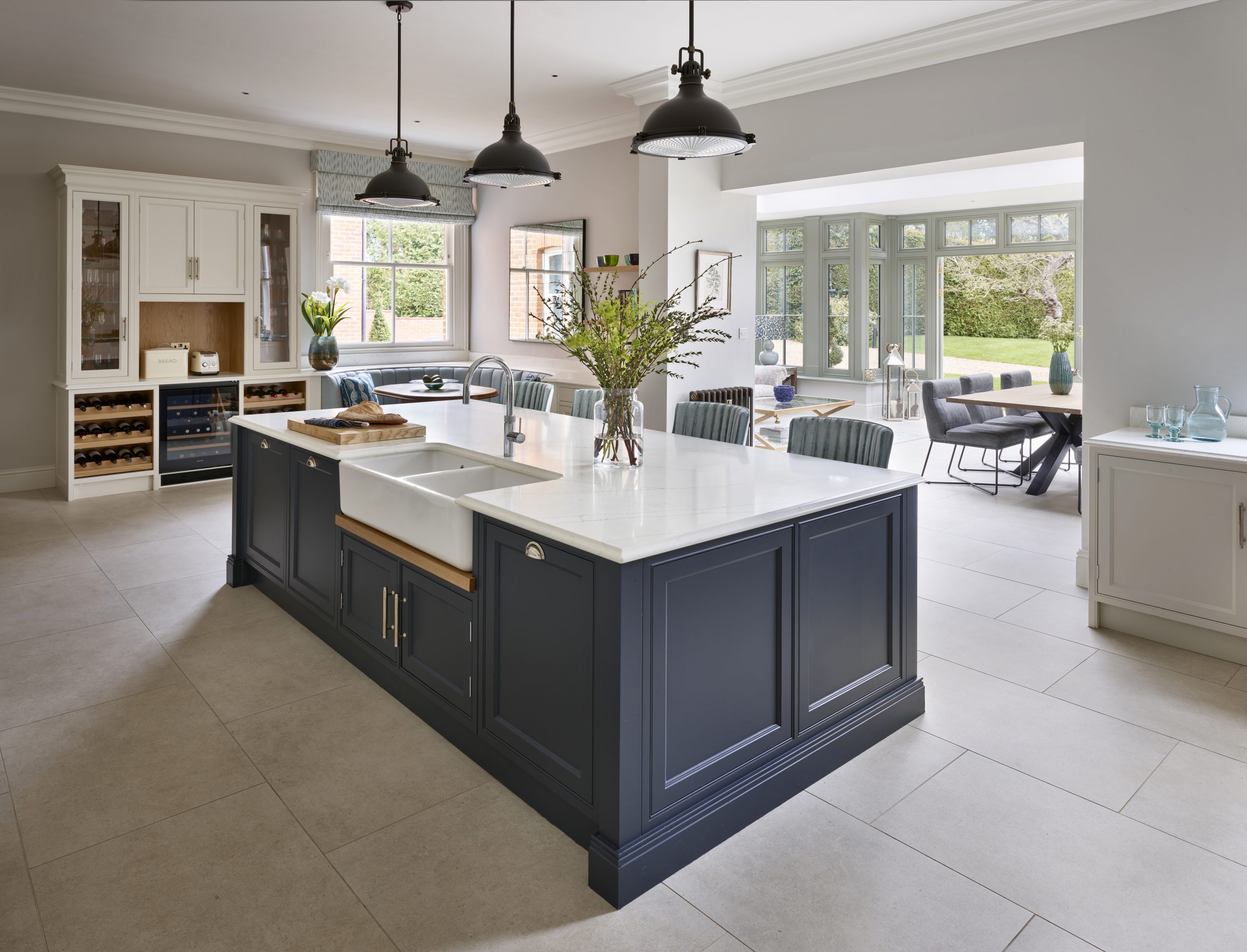 Classic luxury kitchen with large deep blue island with belfast sink and bar seating. 